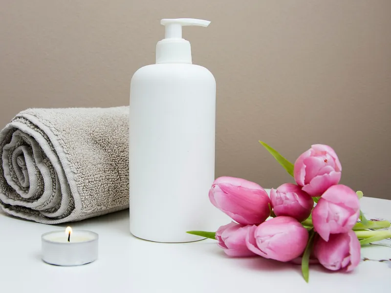 Khăn cuộn, lọ tinh dầu và nến đặt cạnh hoa tươi